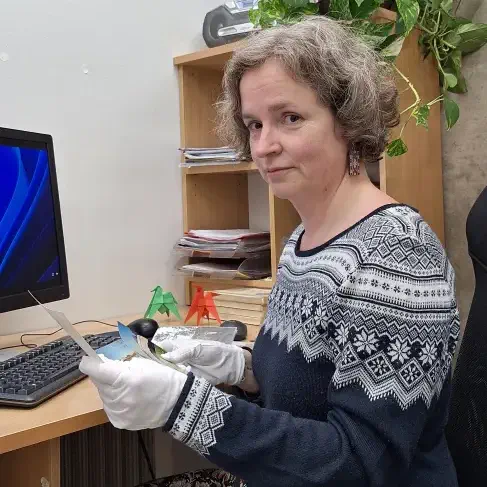 Krista toimetab ettevaatlikult paberfotodega. Jääb mulje, nagu tuleks fotodega ümber käia siidikinnastes, kuid tegelikult on kindad puuvillased.